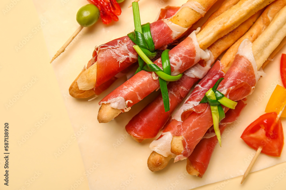 Tasty Italian Grissini with bacon on yellow background, closeup Tasty Italian Grissini with bacon on yellow background, closeup