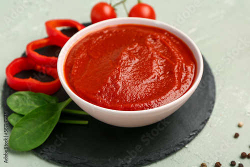 Bowl with tasty tomato paste, peppercorn and spinach on green grunge background