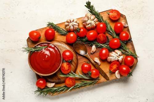 Bowl with tasty ketchup and fresh vegetables on light background