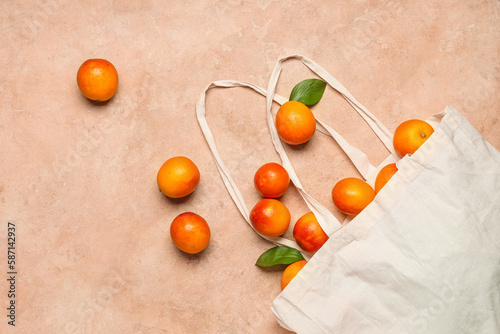 Eco bag with scattered tasty blood orange fruits on beige background