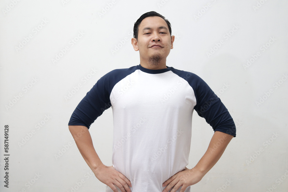 Proud Asian man looking at camera and smiling, hands on hip, shows his self pride confidence Proud Asian man looking at camera and smiling, hands on hip, shows his self pride confidence