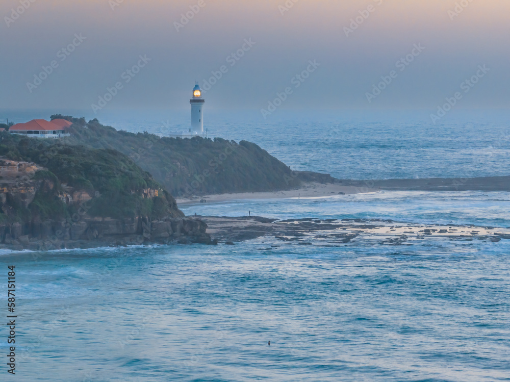 Aerial sunrise seascape with lighthouse, high tide and rock platform
