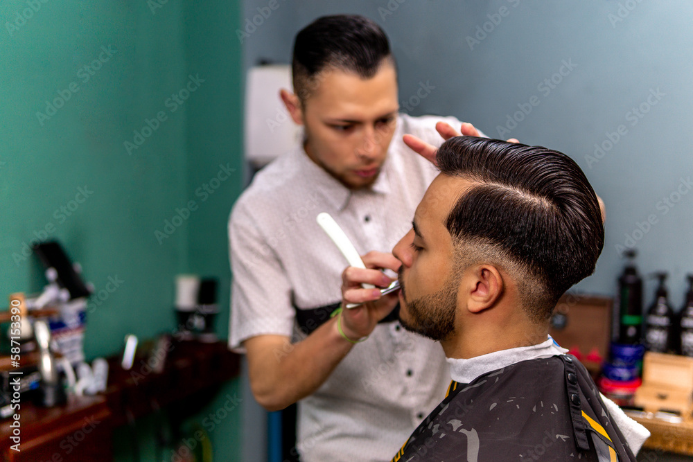 barber with razor thinning client's beard. focus on the hair barber with razor thinning client's beard. focus on the hair