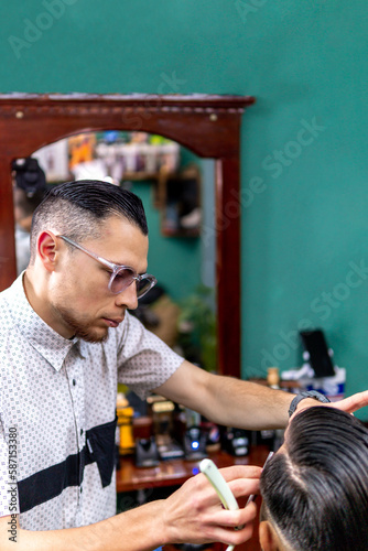 barber with razor thinning client's beard. photo