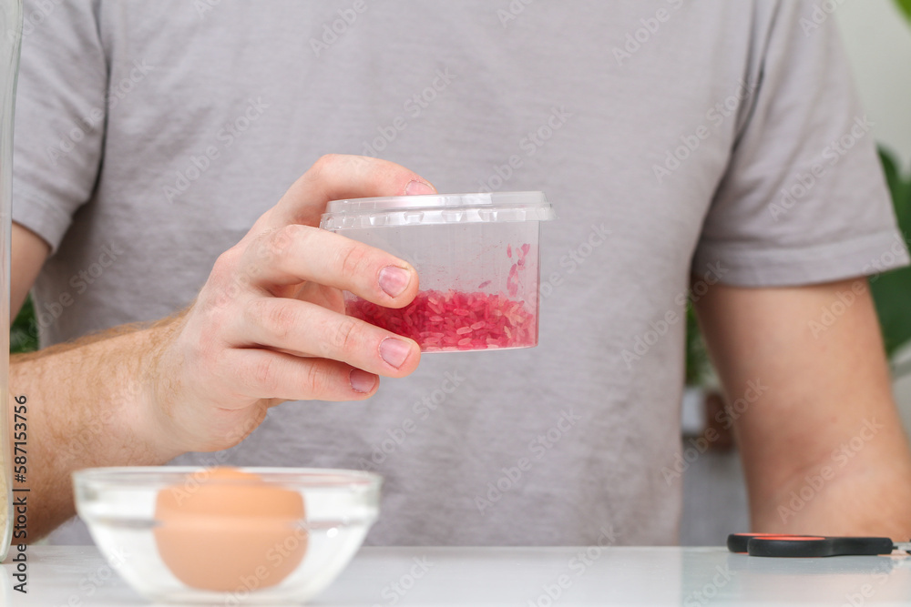 A man shakes container of rice evenly color rice. An unusual way coloring and decorating Easter eggs A man shakes container of rice evenly color rice. An unusual way coloring and decorating Easter eggs