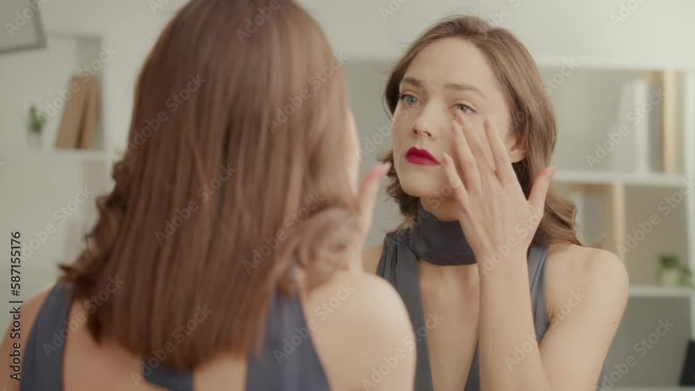Back View of Worried Young Woman with Red Lips in Front of the Mirror. Upset Woman in a Dress Corrects Her Make-up and, Having Gained Confidence, Goes on an Event. Concept of Love Yourself. Back View of Worried Young Woman with Red Lips in Front of the Mirror. Upset Woman in a Dress Corrects Her Make-up and, Having Gained Confidence, Goes on an Event. Concept of Love Yourself.