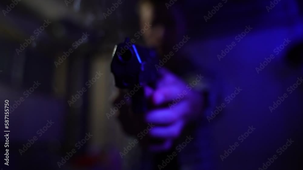 Shot from a black gun pointing downwards towards the camera with a shaky person standing in the baloo-lit basement Shot from a black gun pointing downwards towards the camera with a shaky person standing in the baloo-lit basement