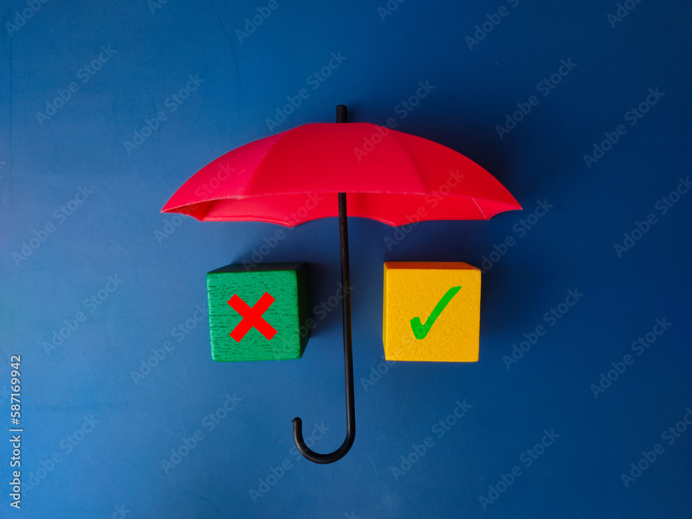 Red umbrella and colored cube with sign wrong and right on blue background.