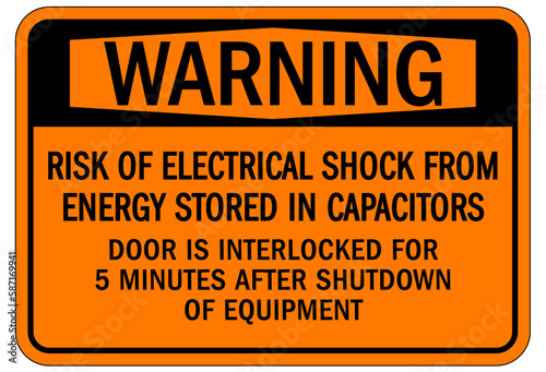 Door safety sign and labels risk of electrical shock from energy stored in capacitor. Door is interlocked for 5 minutes after shutdown of equipment