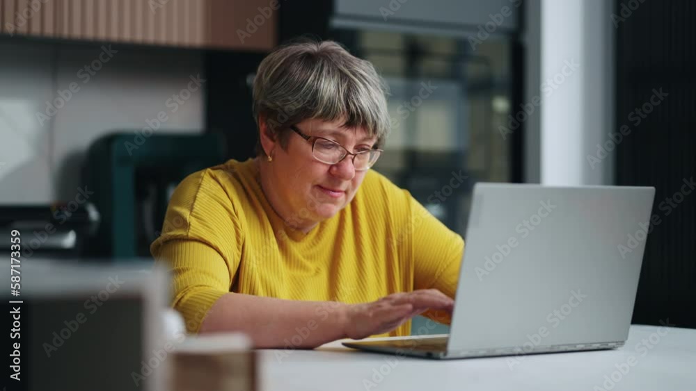 Grandmother Surfing Internet By Modern Laptop At Home, Portrait Of Aged Lady Sitting At Table Grandmother Surfing Internet By Modern Laptop At Home, Portrait Of Aged Lady Sitting At Table