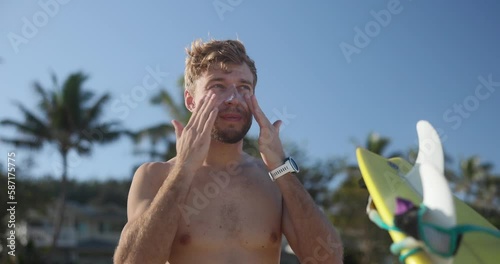 Surfer man putting a sunscreen on his face and neck