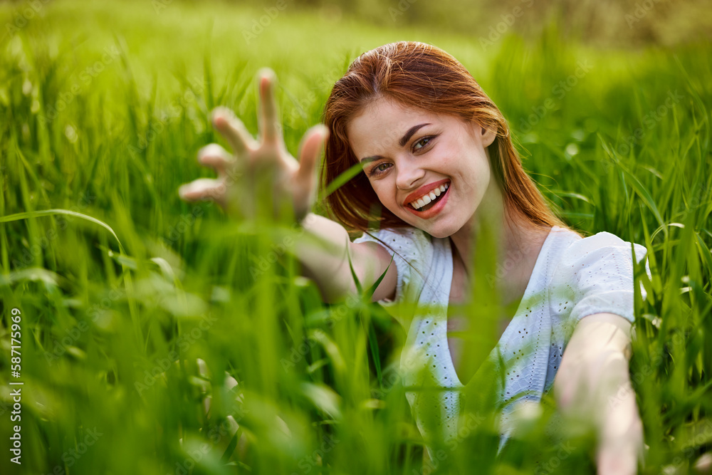 portrait of a broadly smiling woman sitting in tall grass and holding out her hands to the camera portrait of a broadly smiling woman sitting in tall grass and holding out her hands to the camera