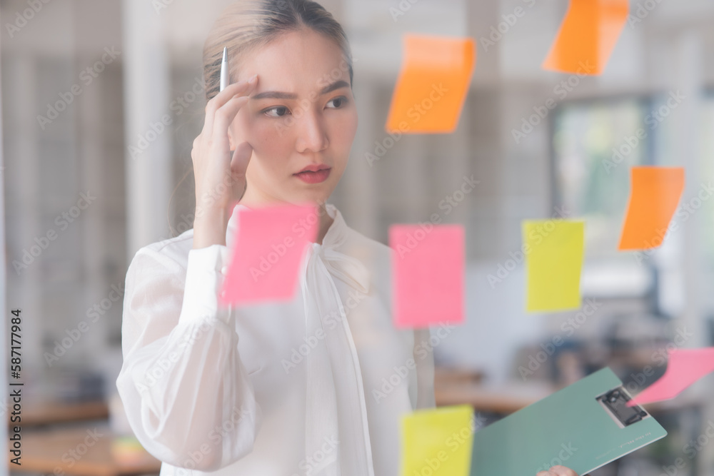 Young Asian businesswoman holding a note on the board presenting about financial business Young Asian businesswoman holding a note on the board presenting about financial business