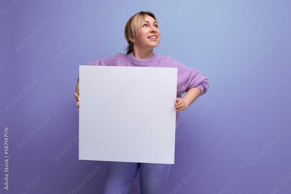 attractive blond woman holding a sheet of paper with a mockup for a promotion message on a purple background attractive blond woman holding a sheet of paper with a mockup for a promotion message on a purple background
