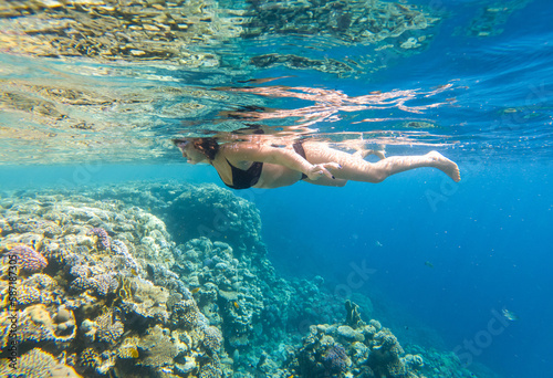 The girl swims underwater in the sea.