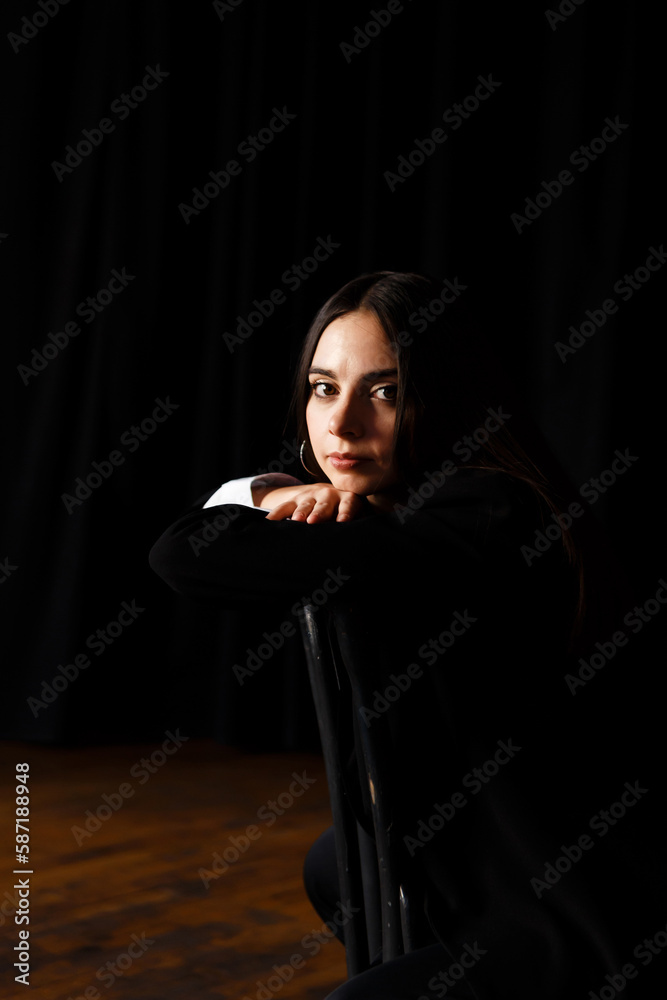 young actress sits on a chair in the rehearsal hall of the theater