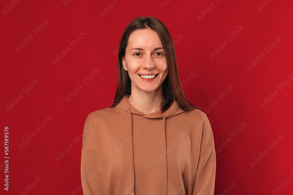 Simple studio portrait of a young wide smiling woman over dark red background. Simple studio portrait of a young wide smiling woman over dark red background.