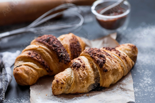 Delicious freshly baked croissants with chocolate on a dark background. French breakfast. Delicious pastries close-up. The context of a bakery with delicious bread. Confectionery products.