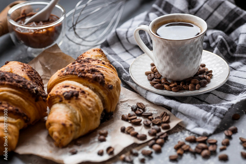 Delicious freshly baked croissants with chocolate and coffee on a dark background. French breakfast. Delicious pastries close-up. The context of a bakery with delicious bread. Confectionery products.