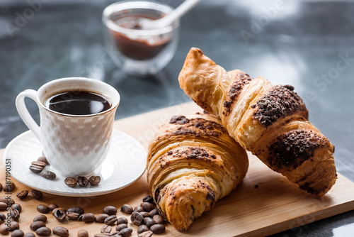 Delicious freshly baked croissants with chocolate and coffee on a dark background. French breakfast. Delicious pastries close-up. The context of a bakery with delicious bread. Confectionery products.