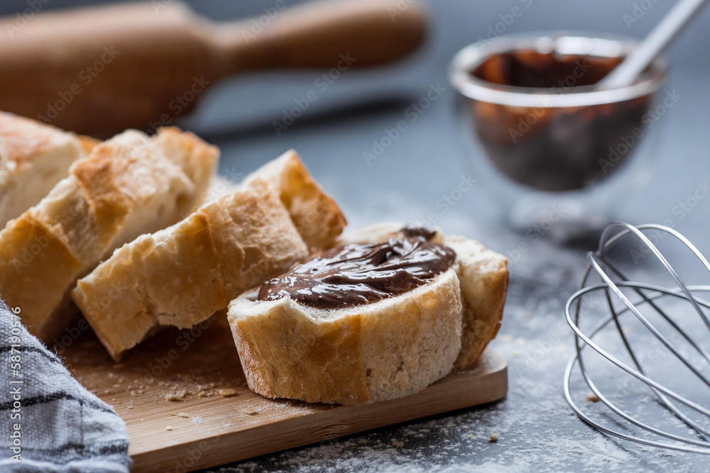 Delicious freshly baked baguette with chocolate on a dark background. French breakfast. Delicious pastries close-up. The context of a bakery with delicious bread. Confectionery products.