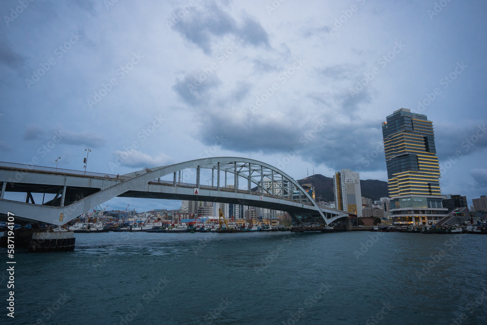 Fototapeta premium Busan Sea Port city view and Busan bridge during winter evening cloudy day at Jung-gu , Busan South Korea : 9 February 2023