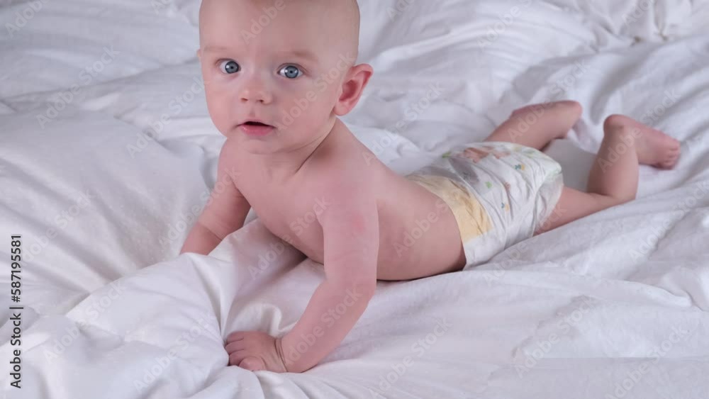 Cute baby boy 6 months old or half a year baby rejoices, has fun and laughs and learns to crawl on a light or white background Cute baby boy 6 months old or half a year baby rejoices, has fun and laughs and learns to crawl on a light or white background