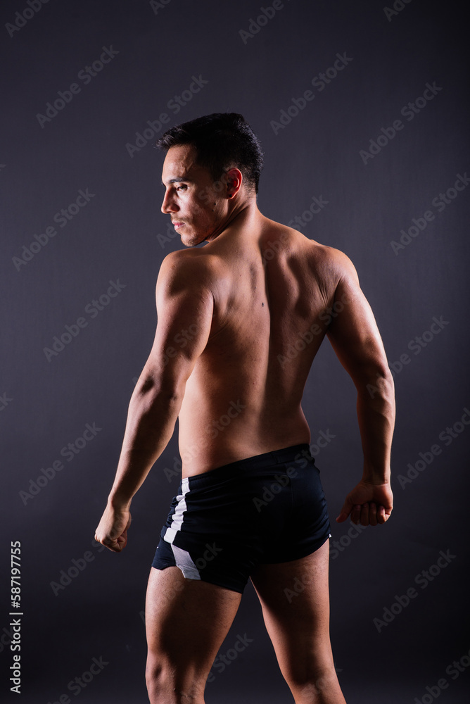 Handsome muscular shirtless young man standing confident, front view, looking at camera