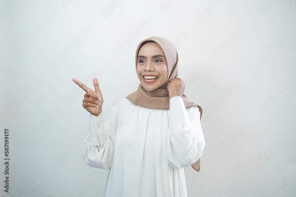 Naklejka premium Cheerful beautiful Asian woman in white dress pointing fingers aside at copy space isolated over white background