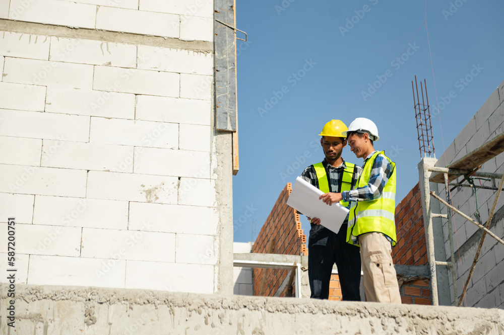 Contractor and architect looking at plan, tablet, laptop and talking about working on big project. Building in construction process interior.