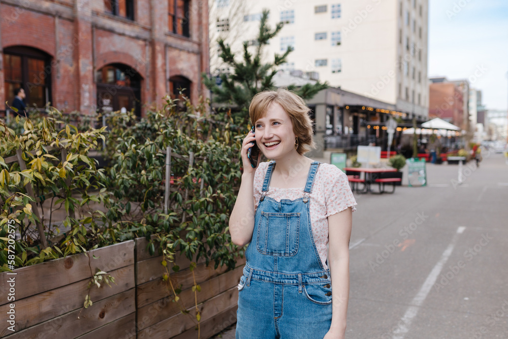 Laughing young woman talking on cell phone downtown Laughing young woman talking on cell phone downtown