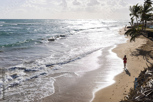 overhead view of woman running on beach with palm trees