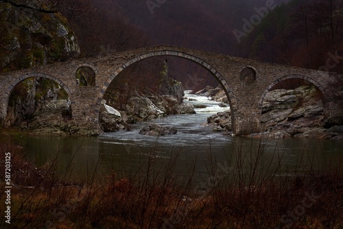 Dyavolski most in Bulgaria landscape. Bridge over the Arda River in a narrow gorge. Near the Bulgarian town of Ardino in the Rhodope Mountains. River with Antic bridg, rainy day. photo