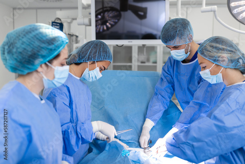 Medical team performing operation. Group of surgeon at work in operating theatre toned in blue. Doctor operation in operation room at hospital concept for insurance advertising.