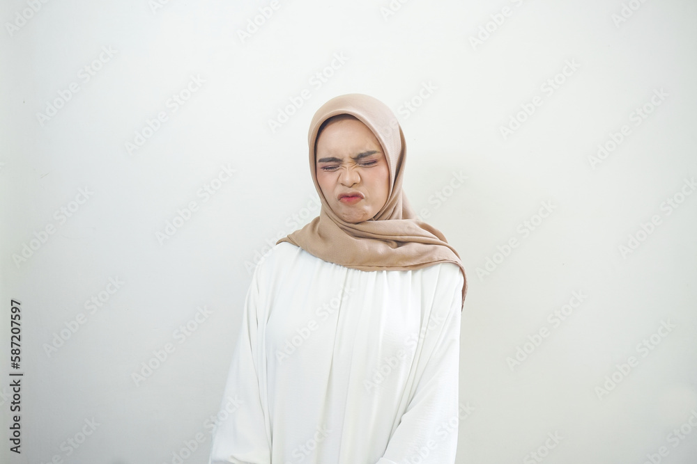 Portrait of sad young Asian muslim woman closed her eyes over isolated white background Portrait of sad young Asian muslim woman closed her eyes over isolated white background