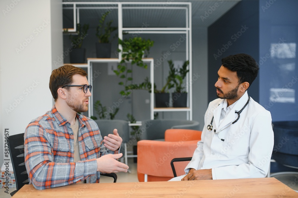medicine, healthcare and people concept - indian doctor young male patient meeting at hospital medicine, healthcare and people concept - indian doctor young male patient meeting at hospital