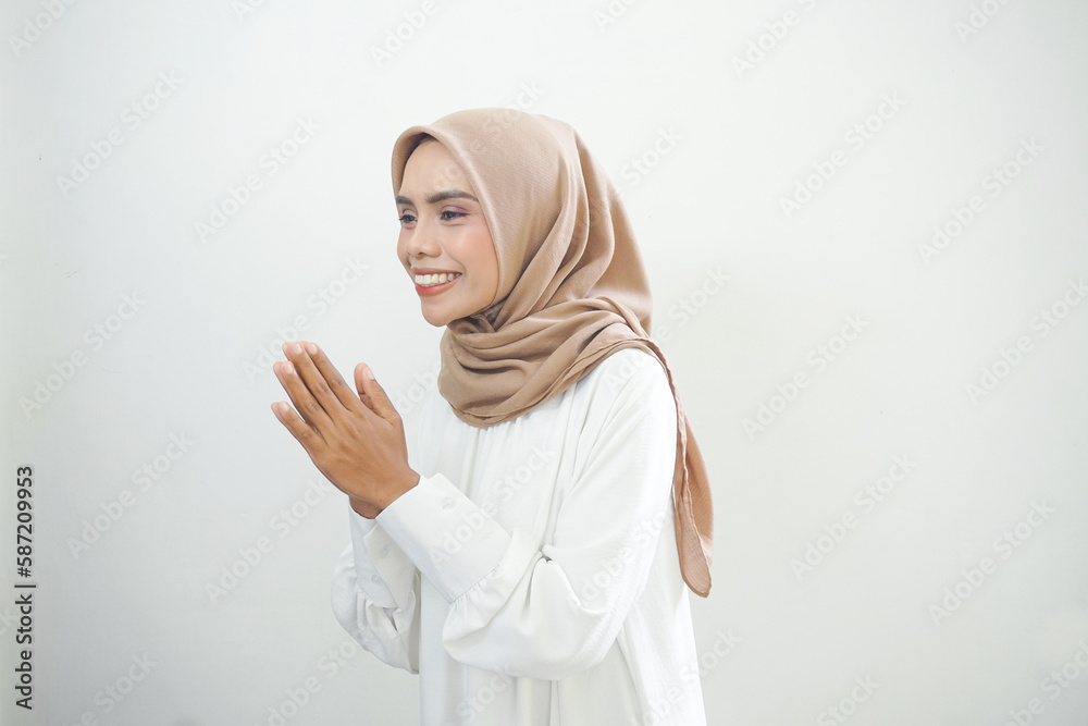 Young Asian Islam woman wearing headscarf gives greeting hands at with a big smile on her face. Indonesian woman on gray background. Eid Mubarak, Eid Fitr, Ramadan