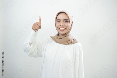 Beautiful smiling Asian woman in white casual showing thumbs up gesture with hand isolated over white background