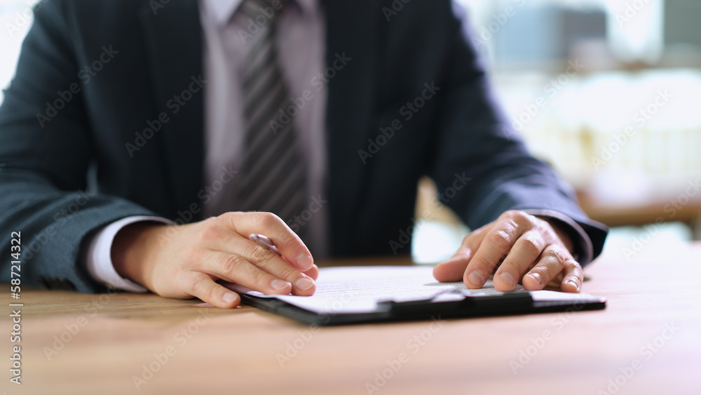 Businessman with pen in hands studying document at table in office closeup. Signing business contract concept Businessman with pen in hands studying document at table in office closeup. Signing business contract concept