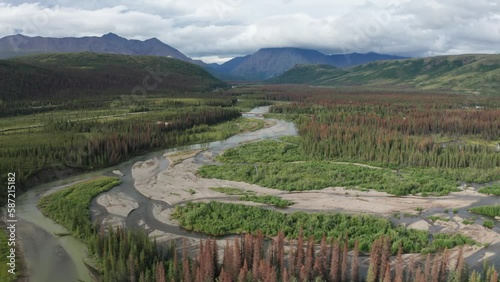 Cantwell River in Alaska during summertime, with a stunning backdrop of mountains, a picturesque bridge, and lush green wilderness. photo