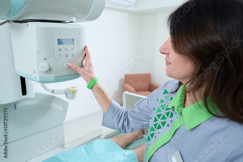 Female radiologist adjusting X-ray machine in hospital