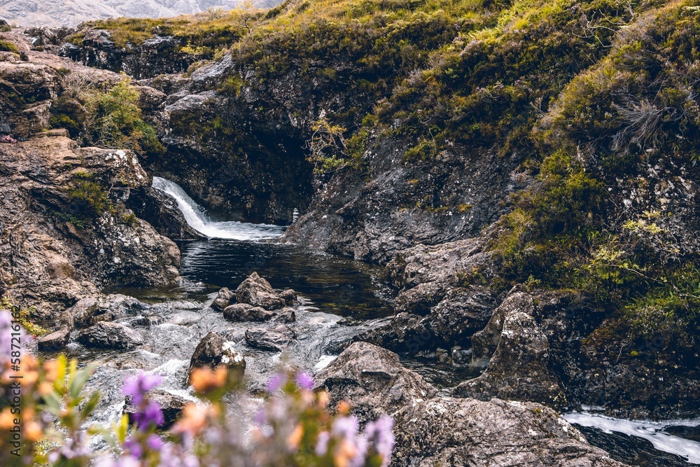 Obraz premium Selective focus of pool the waterfall between rocks covered by grass in the Isle of Skye, Scotland