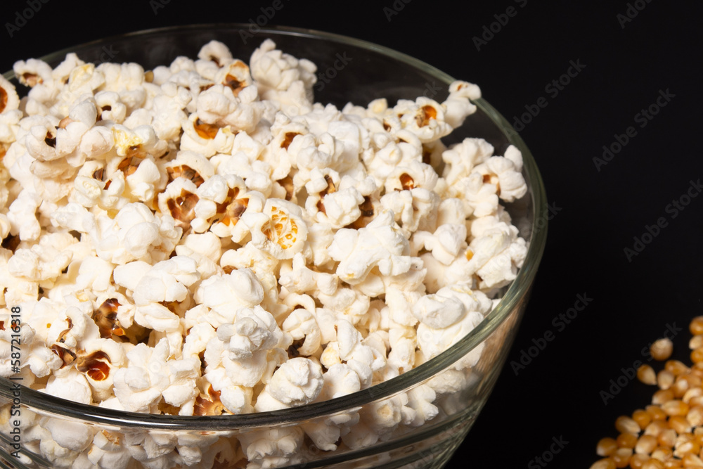 A bowl of fried popcorn and corn kernels on a black background A bowl of fried popcorn and corn kernels on a black background