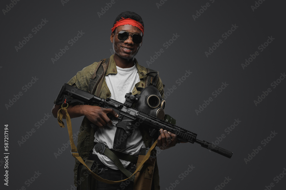 Shot of cheerful pirate of african ethnic with rifle in setting of post apocalypse.