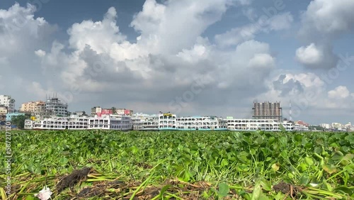 Large yacht and pantoon boats docked in Bangladesh or India. Green vegetation floating in foreground. photo