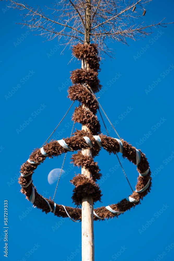 Vertical shot of a Maypole with a blue sky background in Bavaria