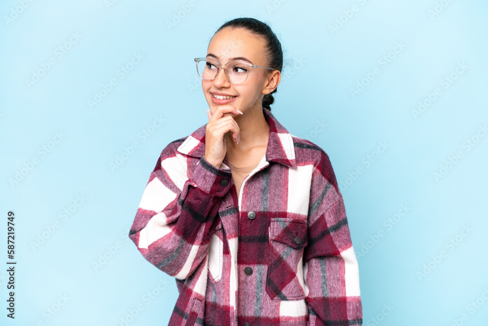 Young Arab woman isolated on blue background looking to the side and smiling Young Arab woman isolated on blue background looking to the side and smiling