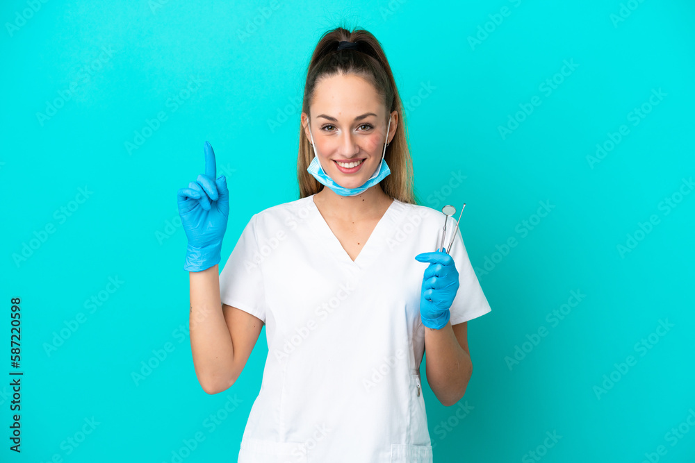 Dentist caucasian woman holding tools isolated on blue background pointing up a great idea Dentist caucasian woman holding tools isolated on blue background pointing up a great idea