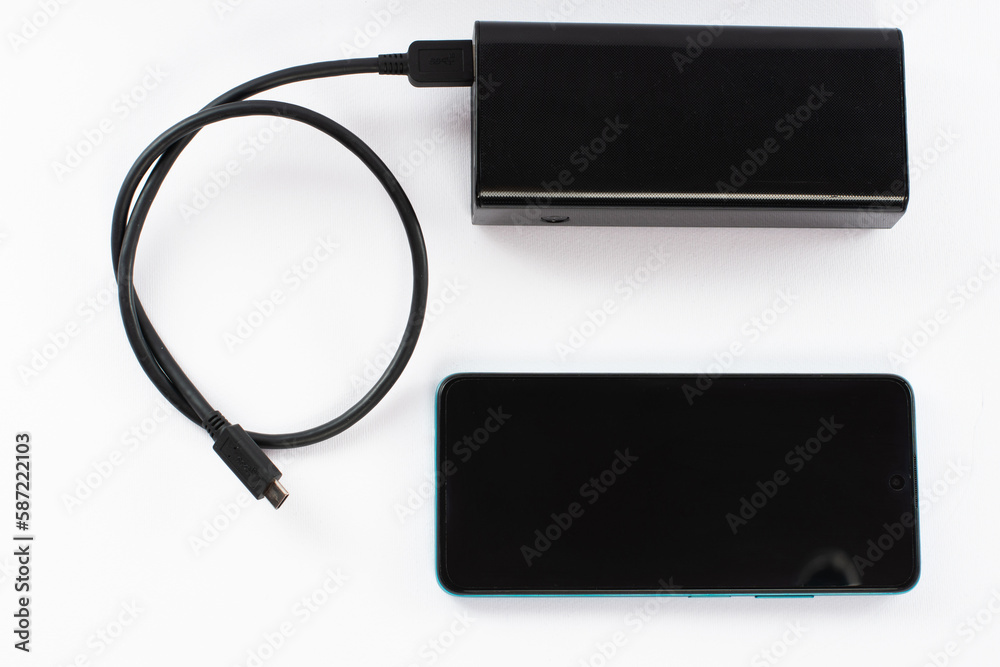 power bank with charging cable and phone, copy space and white background. power bank with charging cable and phone, copy space and white background.