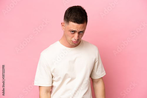 Young Brazilian man isolated on pink background with sad expression
